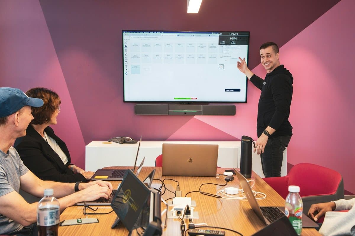 A leader at a wall screen while the team works at laptops