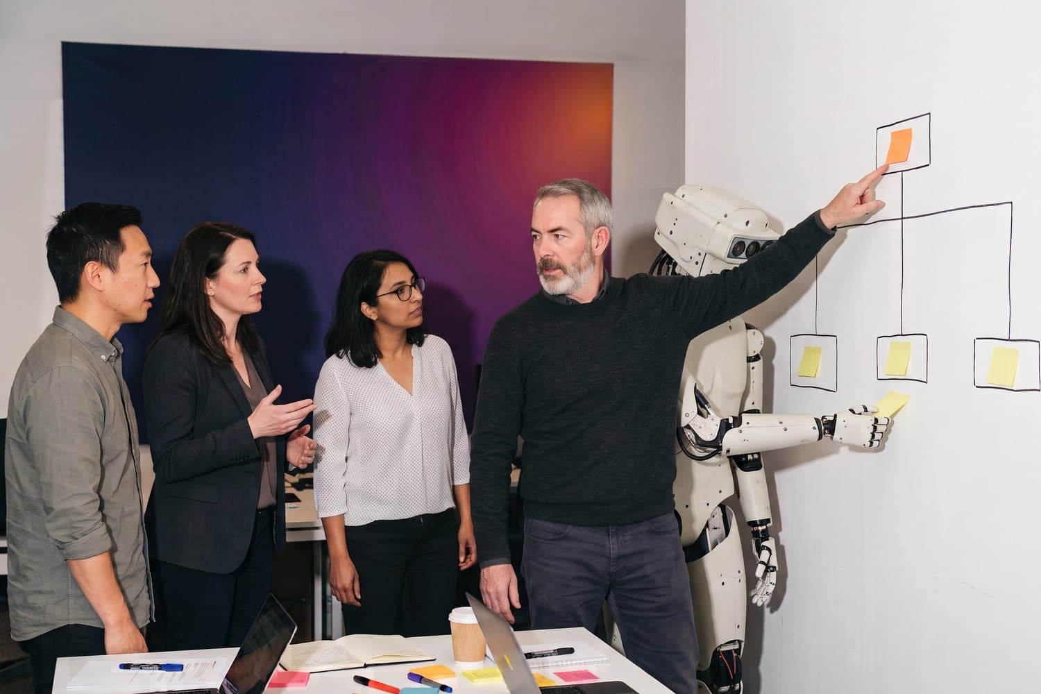 Four colleagues and a humanoid AI agent at a hand-drawn outcome tree; one points at the outcome at the top while the agent adds a sticky note